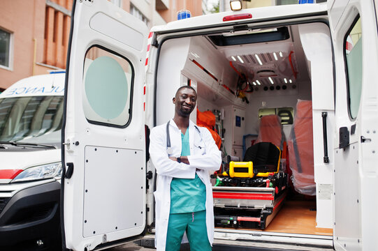 African male paramedic standing in front of ambulance car.