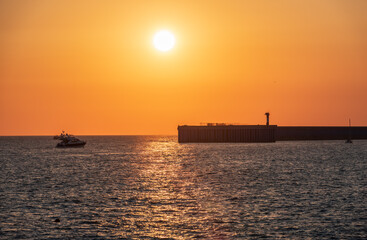 Beautiful yellow and orange sunset over the sea. The sun goes down over the sea. Silhouette of sea port at sunset