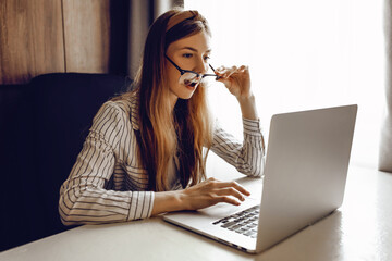 shocked, surprised young student is studying remotely at home on a laptop on the Internet, sitting...
