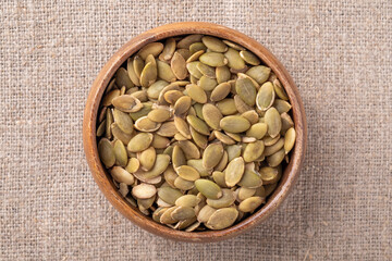 Raw pumpkin seeds in a wooden bowl. Top view