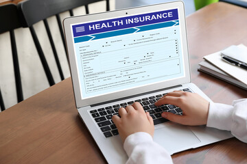 Woman with modern laptop indoors, closeup. Health insurance
