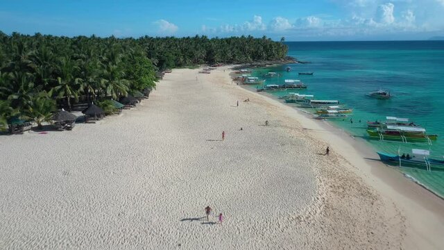 Flying Above Exotic White Beach. Aerial View of People on Sand, Traditional Boats in Sea and Green Tropical Forest
