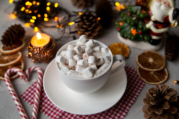 
A cup of hot chocolate and marshmallows stands on a table decorated for Christmas