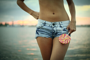 Girl wearied denim shorts is kiping candy near her belly