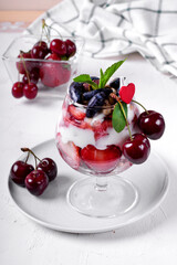 Layered dessert with muesli, berries and yogurt in glass on the white table