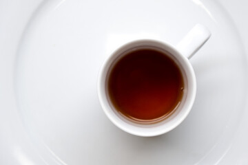 Black refreshing tea and a white mug in a table