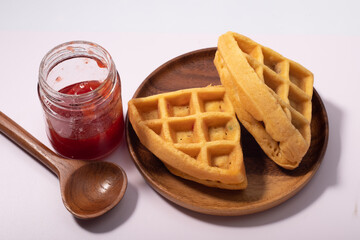 Waffles and strawberry jam on a white background