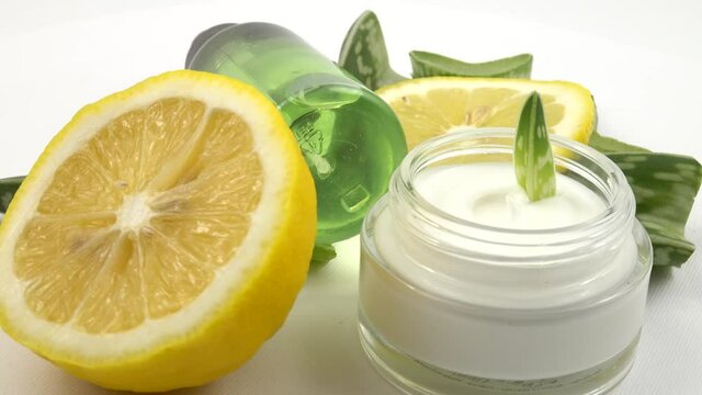 Cosmetics for skin care based on aloe vera and lemon. Jar of face cream and bottle with lotion are laid out on the white background.