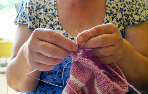 grandmother knits a sweater for her granddaughter with acrylic threads - Powered by Adobe