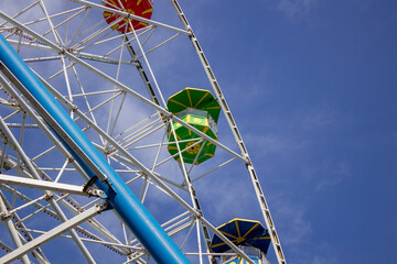 Ferris wheel against the sky. Colorful booths of the Ferris wheel. Bottom view.