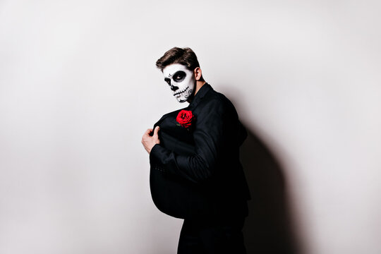Confident brunette man with short hair posing in halloween. Interested guy with face painting fooling around in day of the dead.