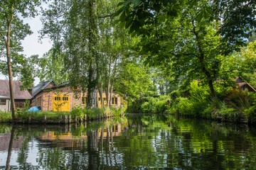 Fototapeta na wymiar Houses at the water canal in biosphere reserve Spree forest (Spreewald) in the state of Brandenburg, Germany.