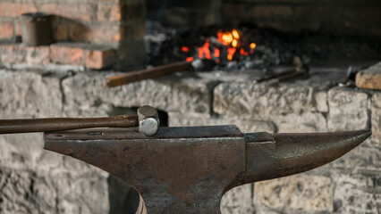 Old smithy - a heavy blacksmiths hammer lies on a huge anvil