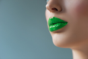 cropped view of woman with green lips isolated on blue