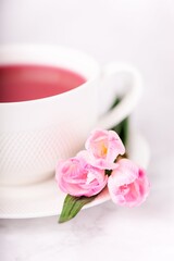 Fototapeta na wymiar Raspberry tea and pink freesia flowers on a white background