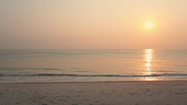 A deserted beach, a change in tide, and a pink and yellow setting sun. Copy space