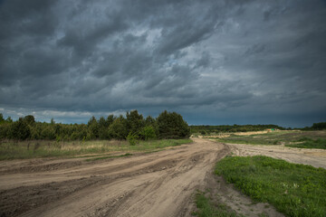 Fototapeta na wymiar A dirt road in a field before a thunderstorm.