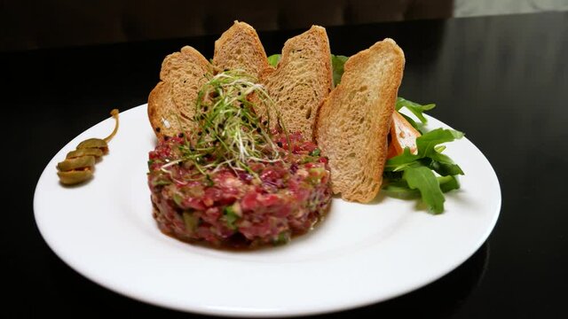 Raw tartar meat with spices, croutons and herbs. Beef tartar with capers. Beef tartar with slices of bread.  Raw meat tartare for gourmet meat.
