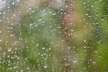 Raindrops on window with green background.