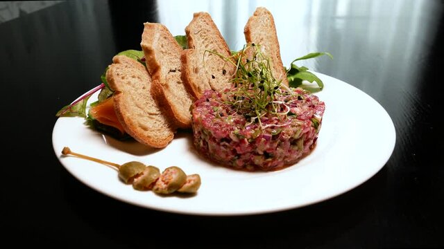 Raw tartar meat with spices, croutons and herbs. Beef tartar with capers. Beef tartar with slices of bread.  Raw meat tartare for gourmet meat.