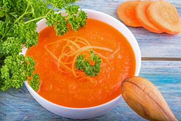 Creamy vegan carrot soup with fresh herbs. Healthy food. Close up. Top view