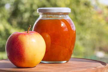 Apple jam in jar with fresh apple on a natural background