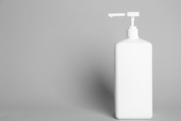 Dispenser bottle with antiseptic gel on light grey background. Space for text