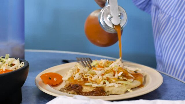 Delicious spicy sauce is generously served on a Salvadoran pupusa with cabbage and carrot salad.