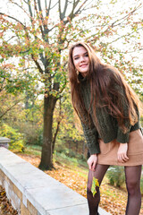 Young woman holding maple leaf in hand outdoor