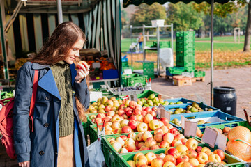 Girl buys fruit and sniffs apple at street market