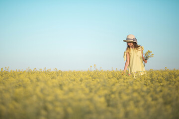 portrait of a beautiful teenage girl in a hat in a yellow field against the sky