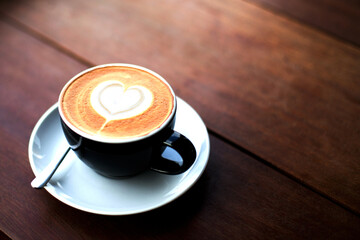 Black cup of tasty cappucino on white soucer