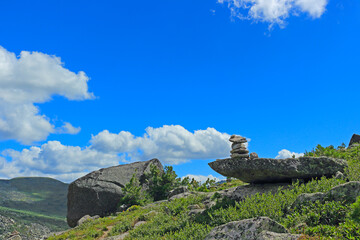 Cairn in mountains against blue sky. Stone pyramid on the mountain trail for the route and protect of the traveler. Zen balanced stones. Nature park Ergaki, Russia, Siberia.