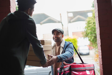 Friendly food delivery man with boxes at front door