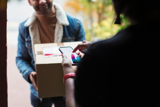 Woman digitally signing smart phone for package at front door