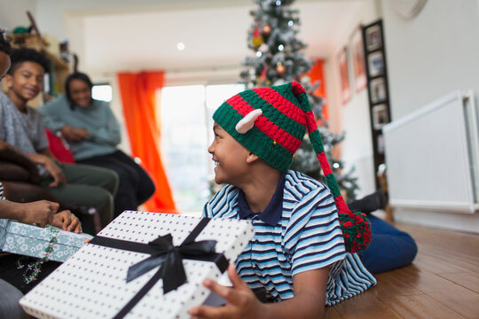 Excited boy opening Christmas gift on living room floor