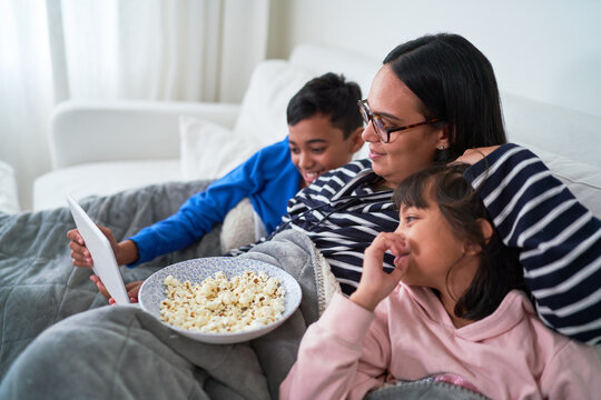 Mother And Kids With Popcorn Watching Movie On Digital Tablet