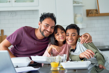 Portrait happy father and kids eating takeout food in kitchen