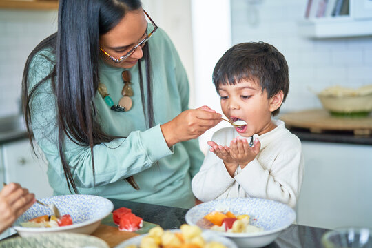 Mother feeding son in kitchen