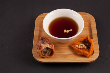 Korean iced fruit tea or chilled punch. It is made from dried persimmons (gotgam) and cinnamon, sometimes ginger and pine nuts are added