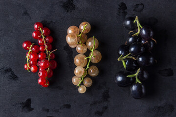 Three types of currants lie on a black background. Red, white and black currants lie next to each other.
