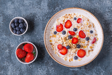 Healthy breakfast, bowl with oat granola, milk and berries.