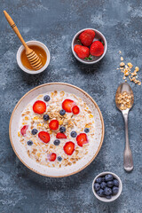 Healthy breakfast, bowl with oat granola, milk and berries.