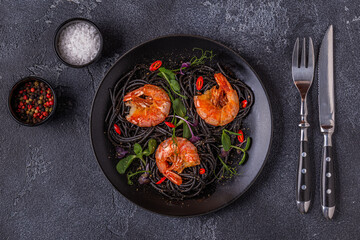 Italian pasta black spaghetti with shrimp and microgreens.