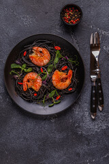 Italian pasta black spaghetti with shrimp and microgreens.