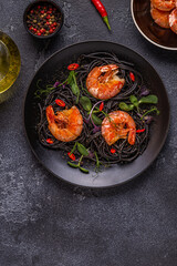 Italian pasta black spaghetti with shrimp and microgreens.