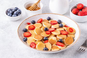 Tiny pancakes with strawberries and blueberries for breakfast.