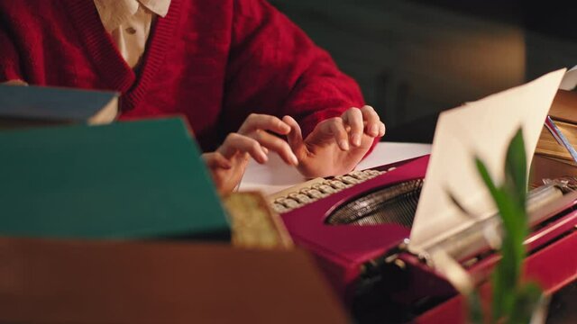 Closeup to the camera in the library lady typing some documents on the pink typewriter. 4k