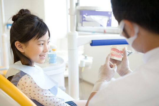 歯型を見せて話す歯科医師と少女