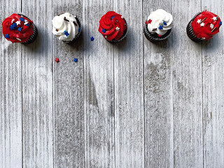 five red and white muffins, on top with decorative stars stand on a white textured wooden board, high quality photo, free space for text, background for the holiday of Independence Day USA